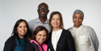 5 staff members in a group smile at the camera