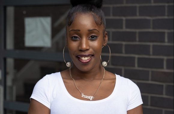 Young woman smiles in front of a building