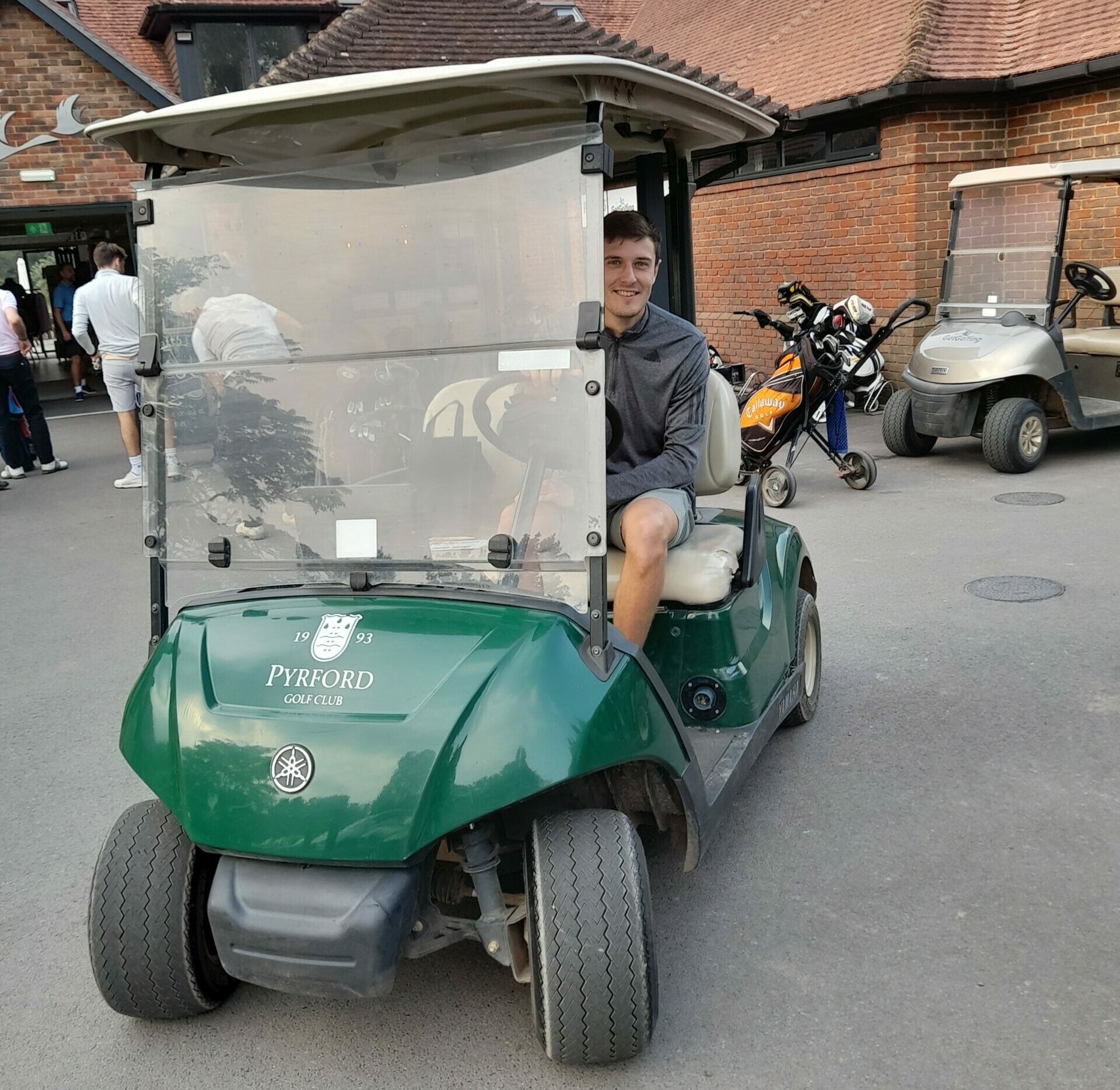 A golfer zooms by in a golf cart.